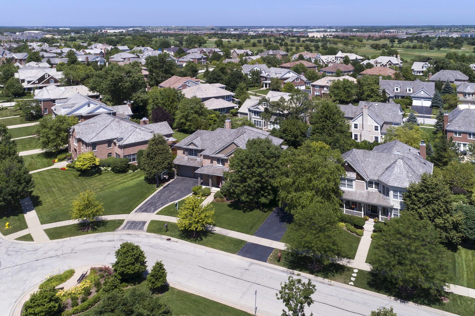 Aerial view of two-story homes with new grey shingle roofs on a suburban cul-de-sac